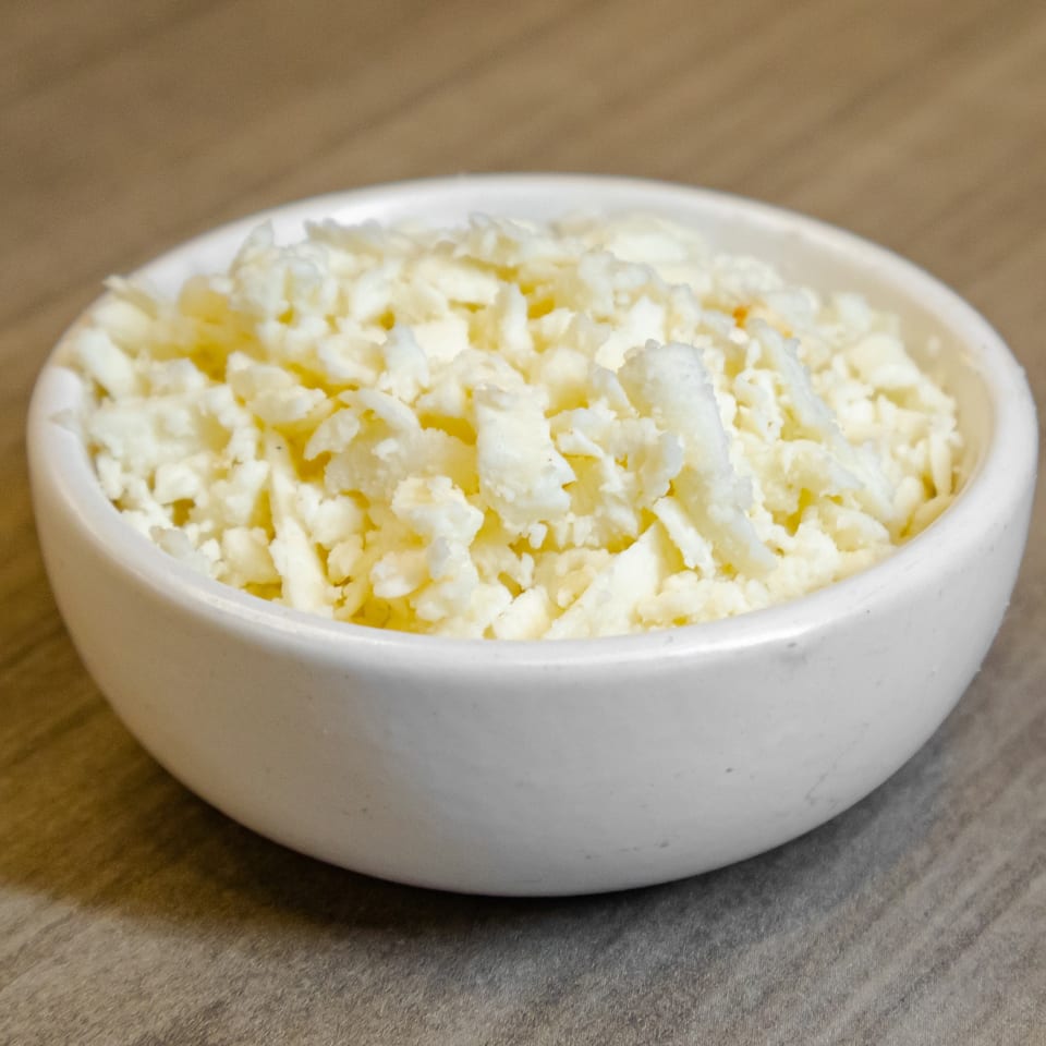 White bowl filled with freshly popped, lightly buttered popcorn on a wooden table.